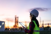 Sundset lady looking in an ipad with a hemlet and yellow saftey west on AdobeStock_378757112