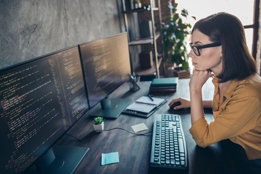 female developer with two screens with code