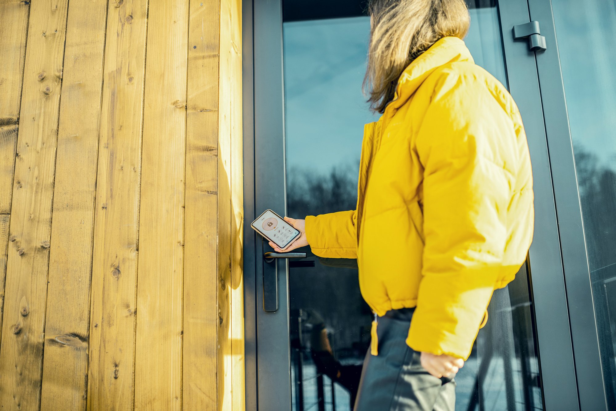 womman_looking_up_door_using_phone_wearing_yellow_jacket_adobestock_308964839.jpg